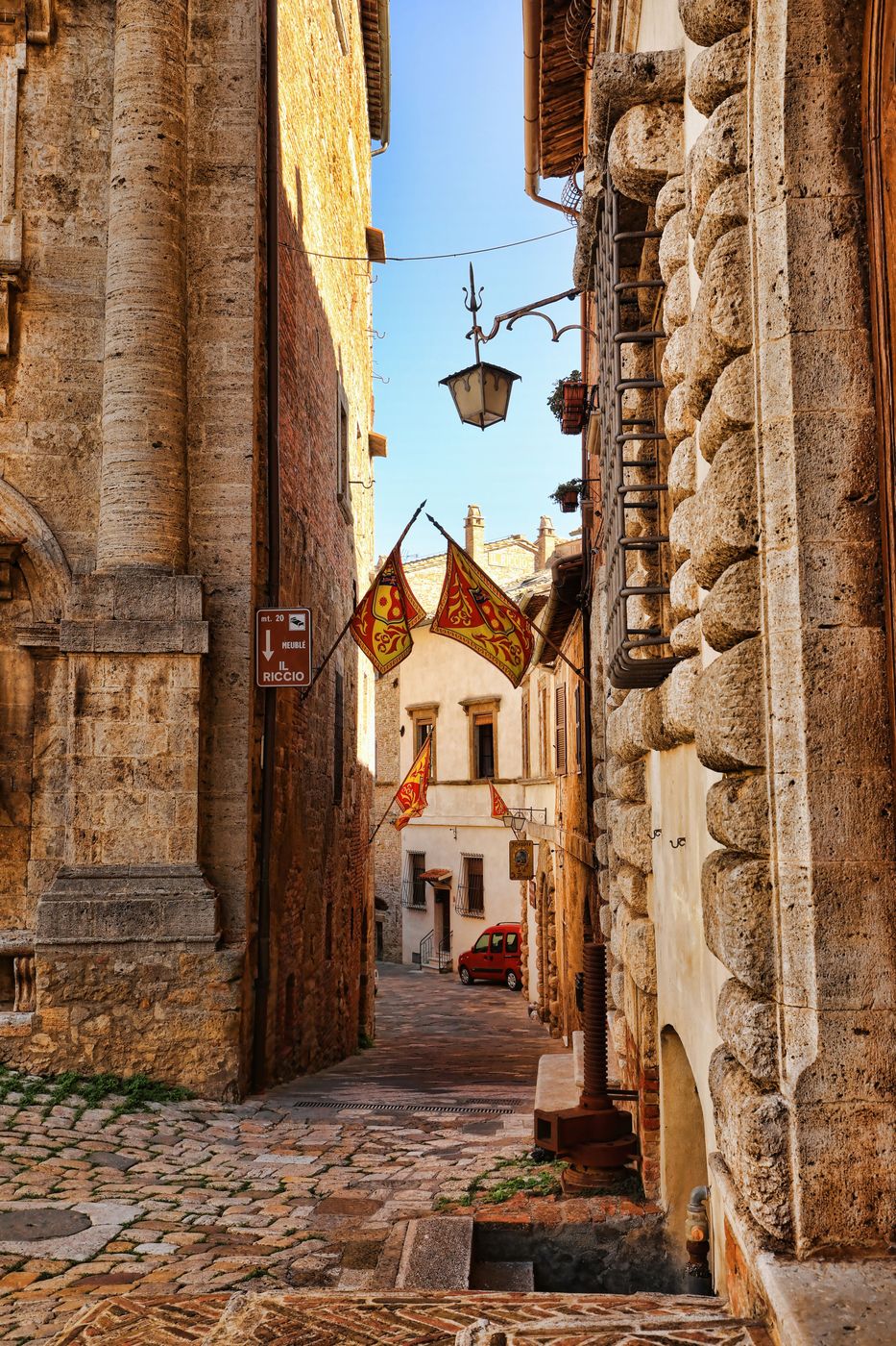 Ruelle pavée de Montepulciano ornée de bannières rouge et or