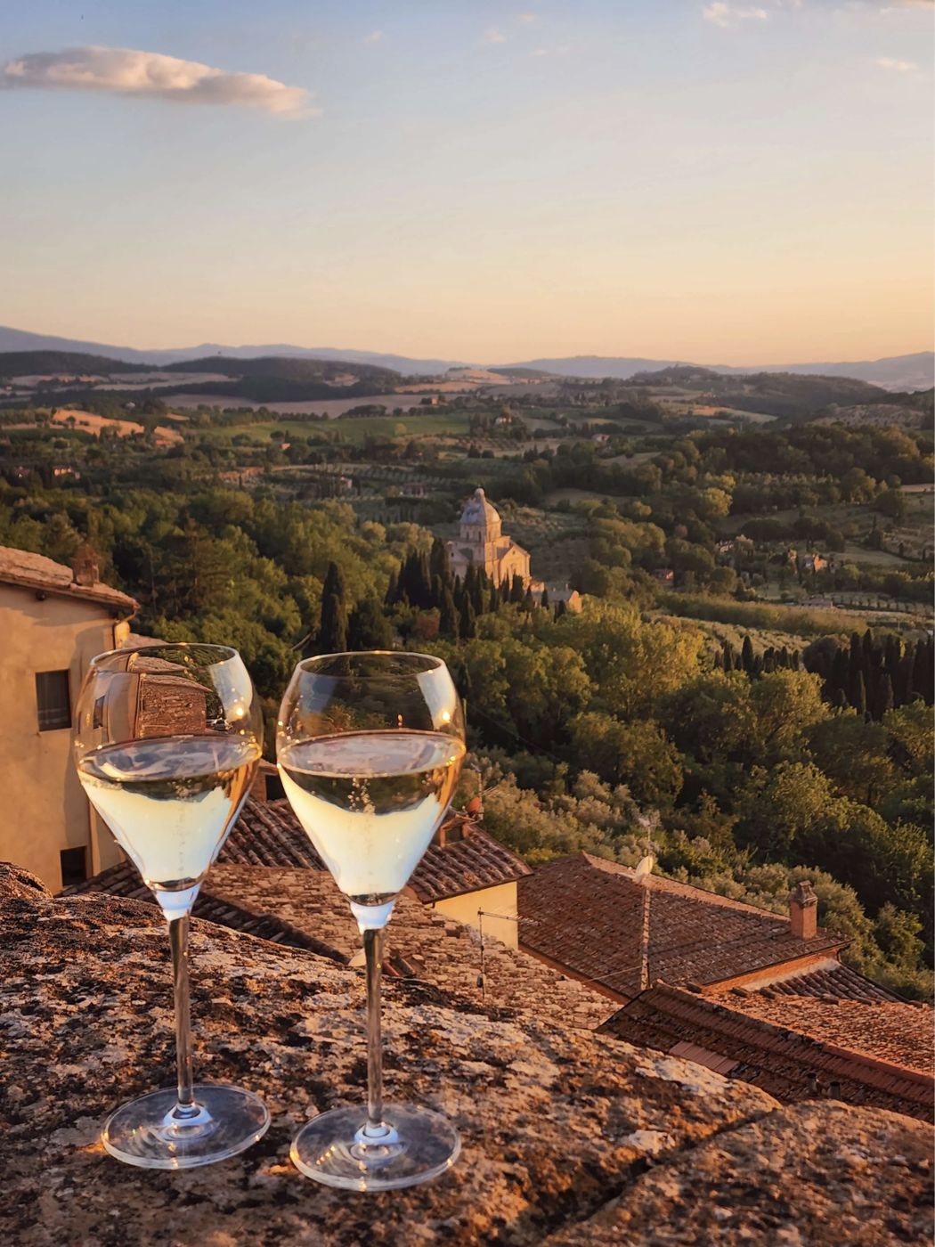 Deux verres de vin blanc sur un muret de Montepulciano, face au Val d'Orcia au coucher du soleil