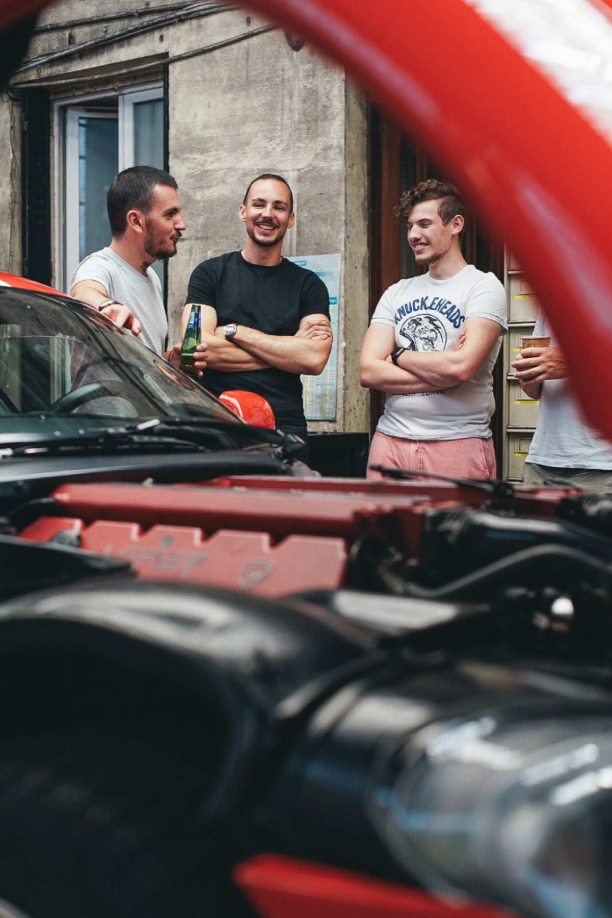 Échanges entre passionnés autour d'une voiture, capot ouvert